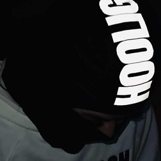 Person wearing a reflective 'Hooligoon' mask at night with city lights in the background