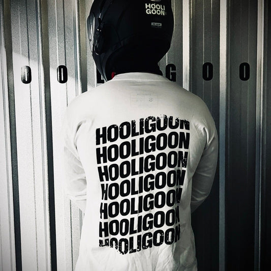 Person wearing a white jacket with 'HOOLIGOON' text, standing against a metallic wall.