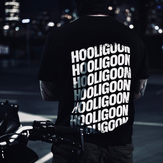Person wearing a black t-shirt with 'HOOLIGOON' text, standing on a rooftop at night.