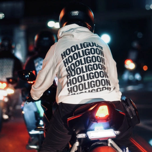 Person riding a motorcycle at night with 'Hooligoon' hoodie