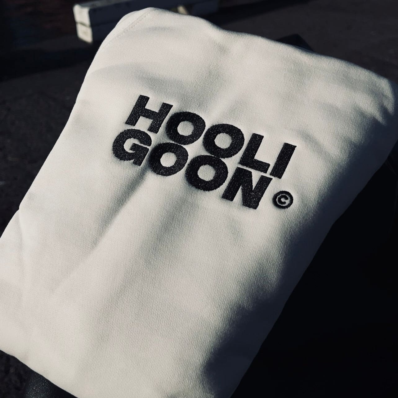 White hoodie with 'HOOLIGOON' text on a dark background