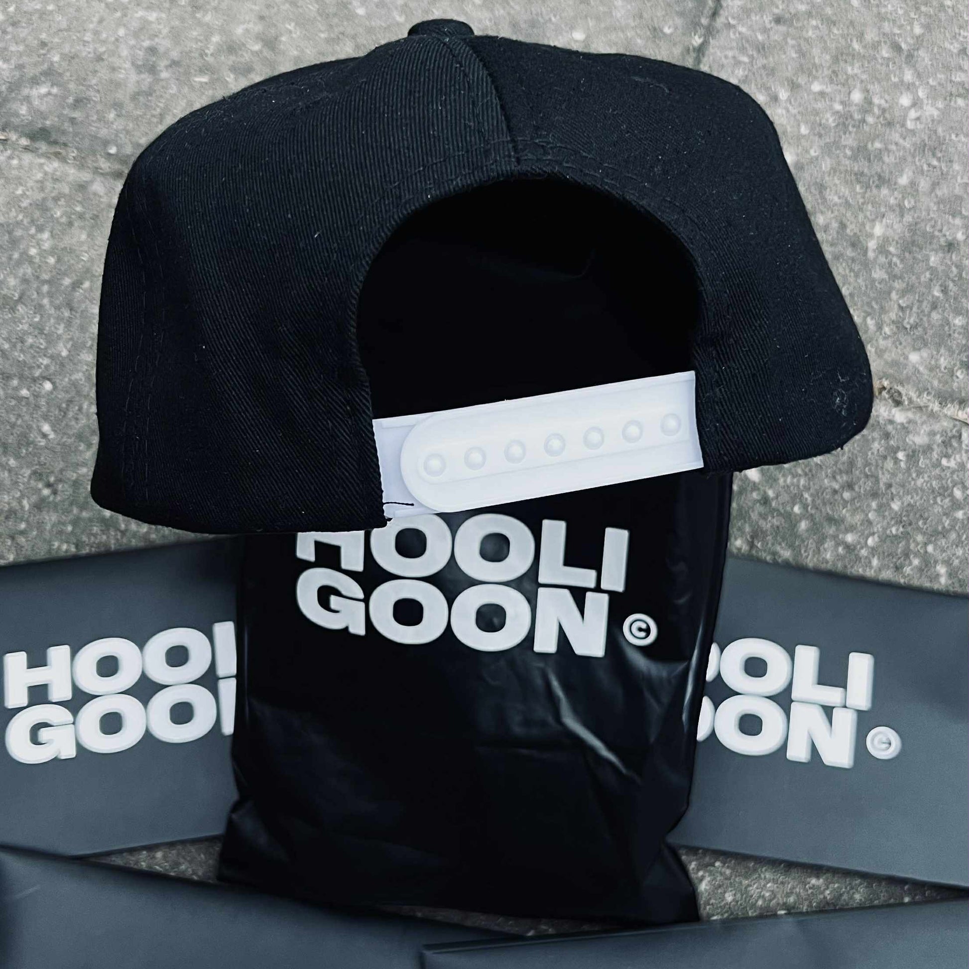 Black cap with 'HooliGoon' branding on a gray surface