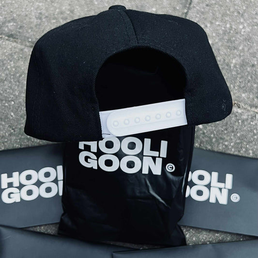 Black cap with 'HooliGoon' branding on a gray surface