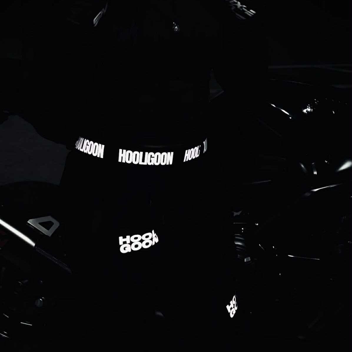 Person wearing a dark hoodie with reflective text in a dark setting
