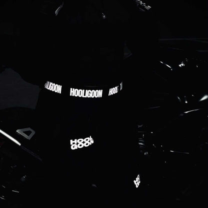Person wearing a dark hoodie with reflective text in a dark setting