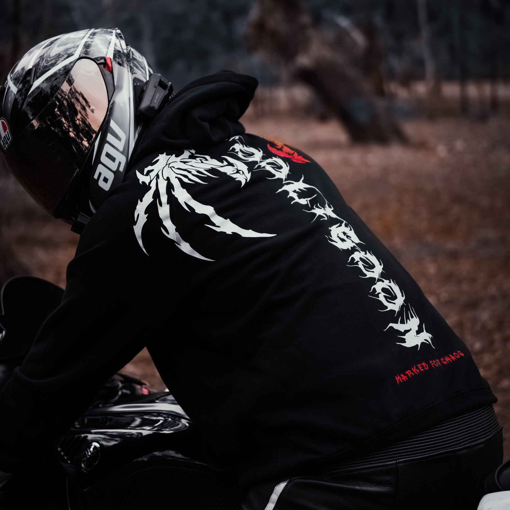 Person wearing a black motocross suit with visible branding in a dark forest setting