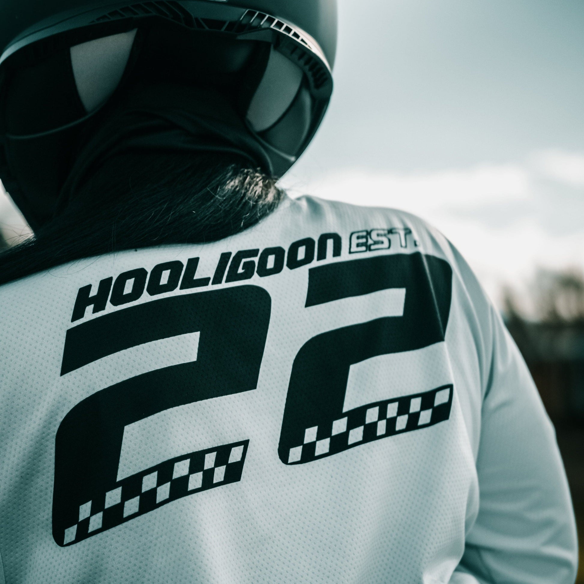 Person wearing a white jacket with 'HOOLIGOON' text and a black helmet with 'LS2' branding.