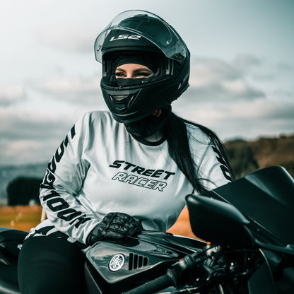 Person wearing a helmet and 'Street Racer' shirt sitting on a motorcycle with a blurred background.