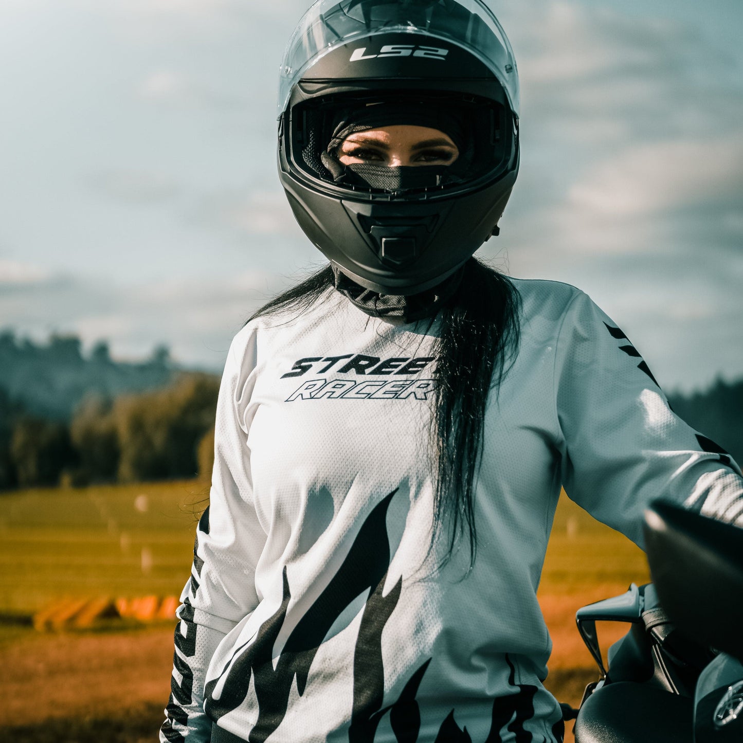 Person wearing a motorcycle helmet and jacket in an outdoor setting