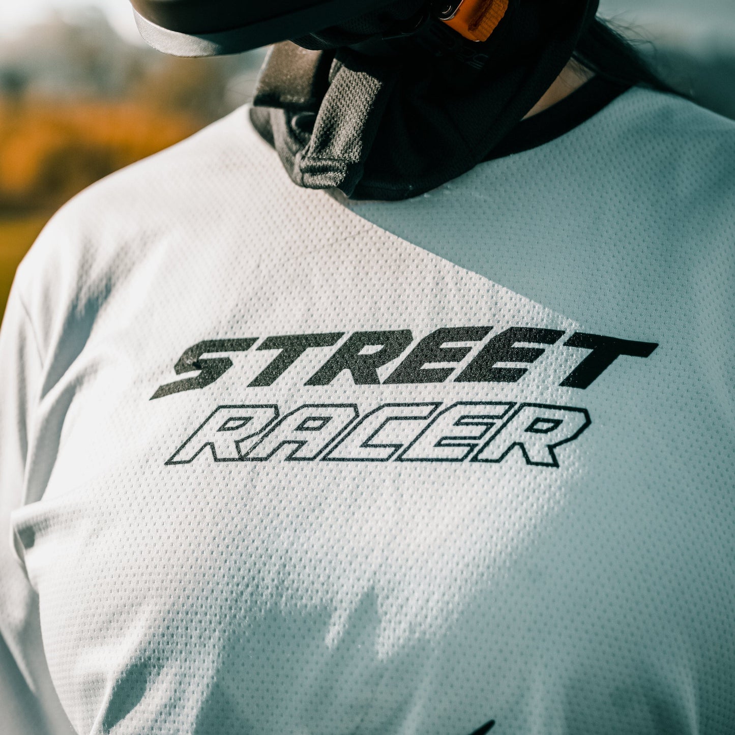 Person wearing a white shirt with 'Street Racer' text and a helmet.