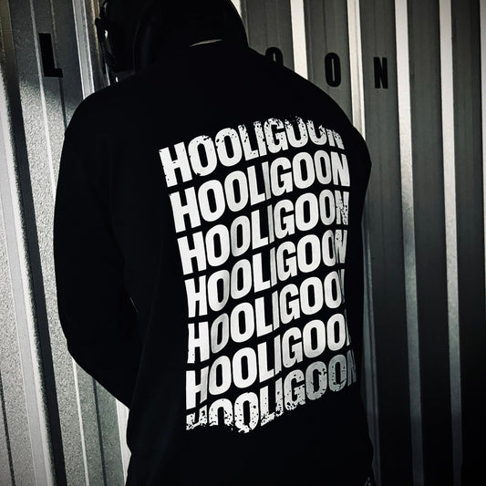 Person wearing a black hoodie with 'HOOLIGOON' text in white, standing in front of vertical blinds.