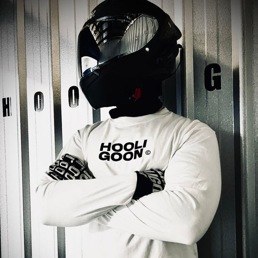 Person wearing a white long-sleeve shirt with 'HOOLIGOON' text, black helmet, and gloves in a locker room.