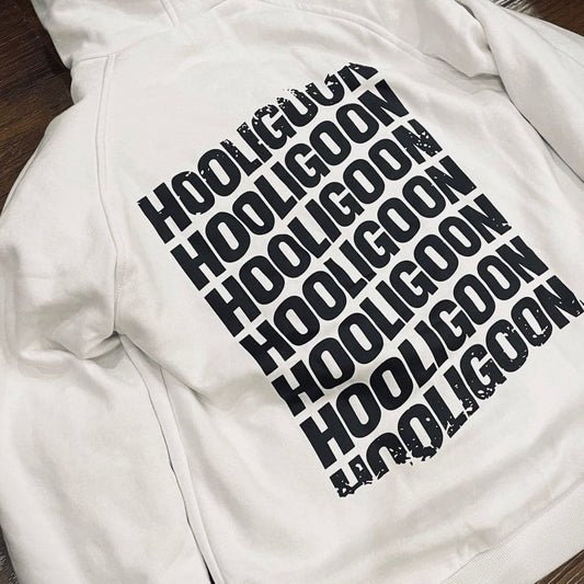 White hoodie with 'HOOLIGOON' text printed in black on a wooden surface