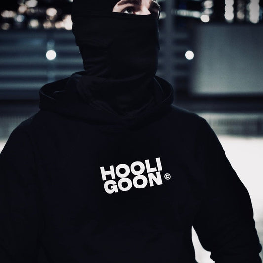 Person wearing a black hoodie with 'HOOLIGOON' text in a dark setting