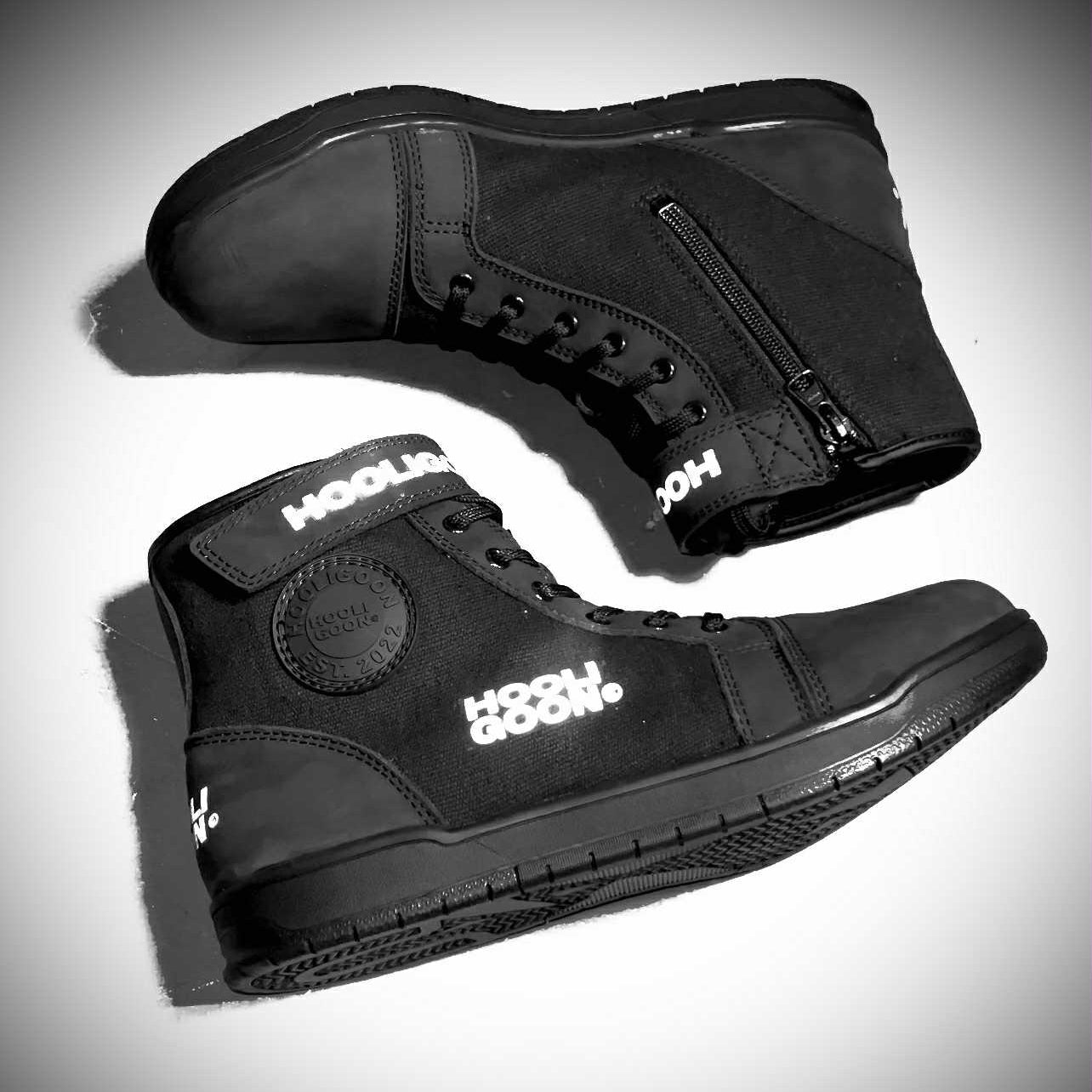 Black high-top sneakers with visible branding on a gray background